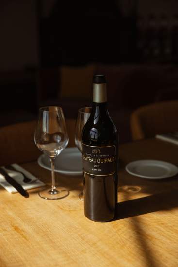 Couverts et bouteille de vin du <span><span><span>Château Guiraud, Visite de Château Vignoble à Sauternes</span></span></span>